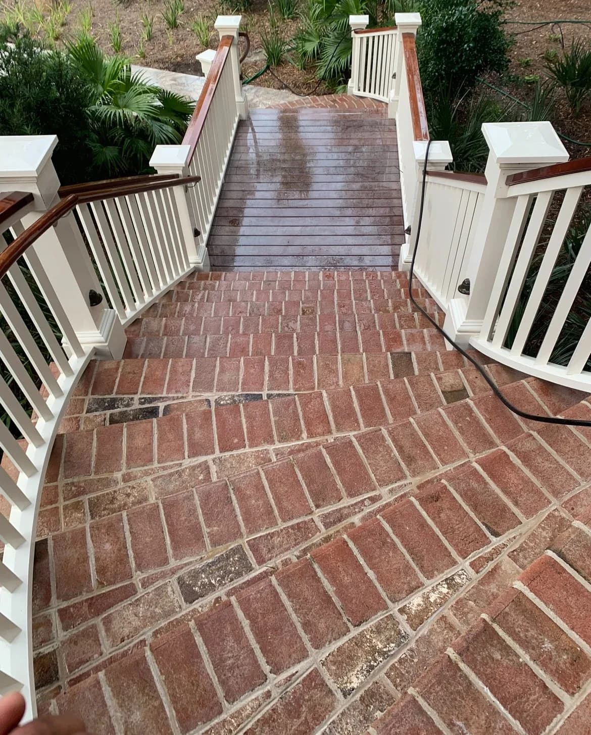 Curved brick walkway with its red brick color restored after pressure washing